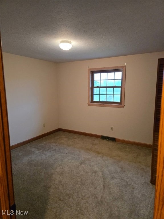 carpeted empty room with a textured ceiling