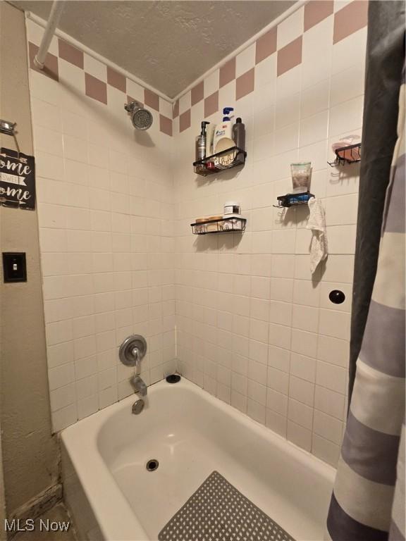 bathroom with a textured ceiling and shower / tub combo