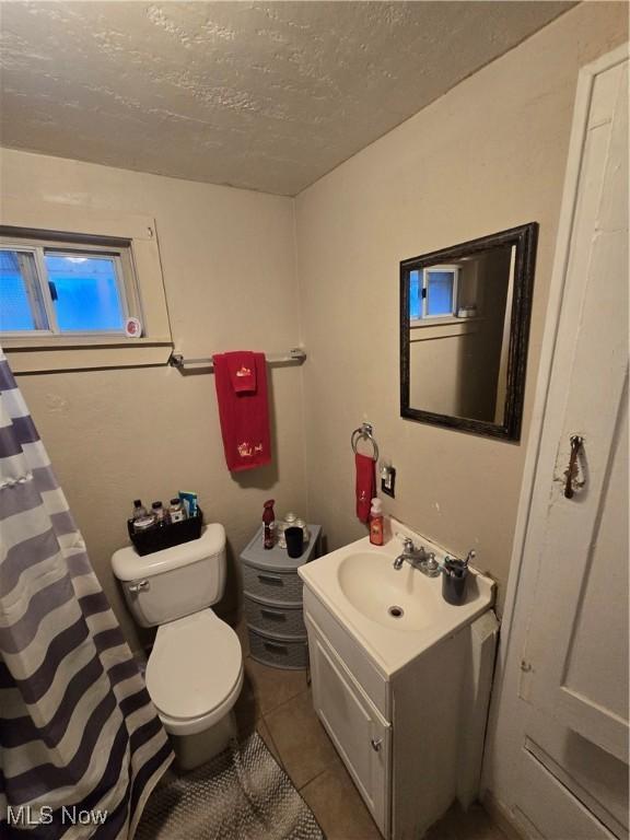 bathroom featuring tile patterned flooring, a textured ceiling, vanity, and toilet