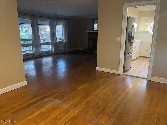 unfurnished room featuring crown molding, a fireplace, and wood-type flooring