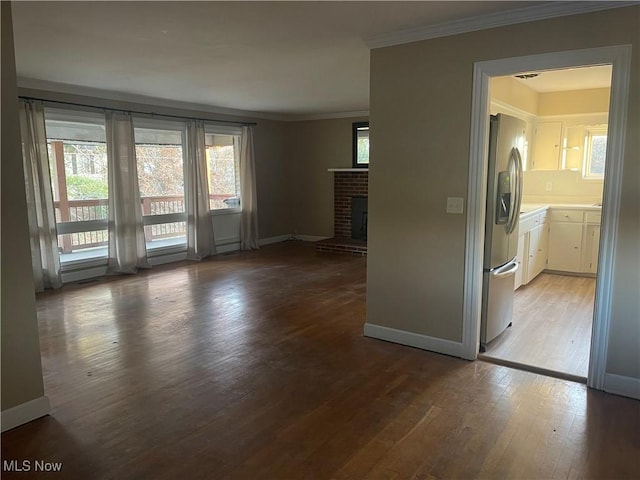 unfurnished living room with wood-type flooring, a brick fireplace, and ornamental molding