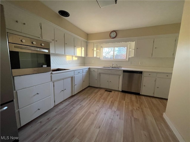 kitchen with white cabinetry, sink, decorative backsplash, appliances with stainless steel finishes, and light wood-type flooring