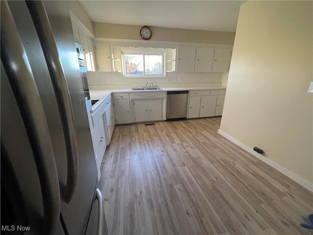 kitchen with white cabinets, appliances with stainless steel finishes, and light hardwood / wood-style floors