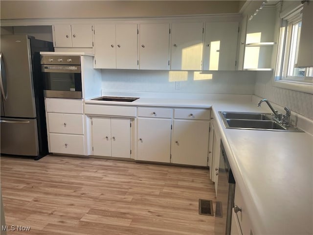 kitchen featuring white cabinets, appliances with stainless steel finishes, light wood-type flooring, and sink