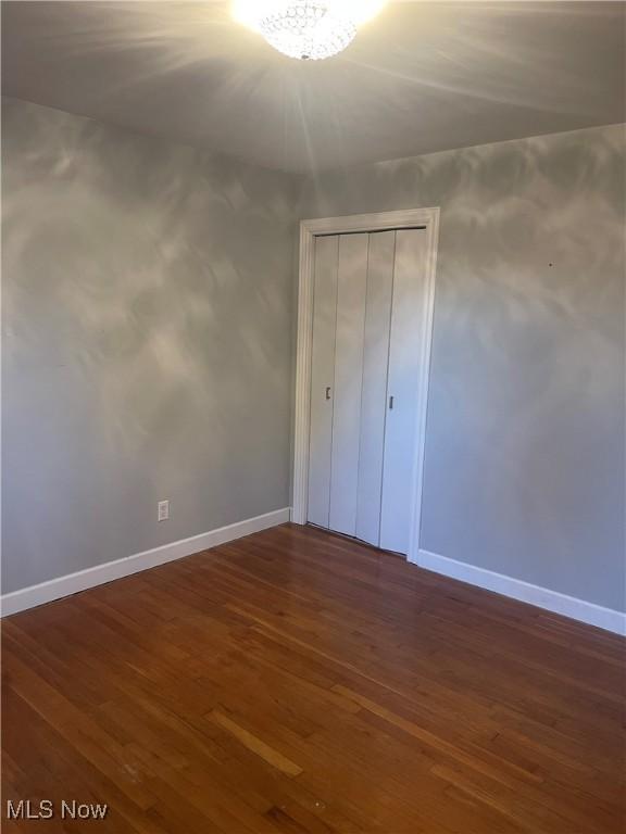 unfurnished bedroom with a closet and dark wood-type flooring