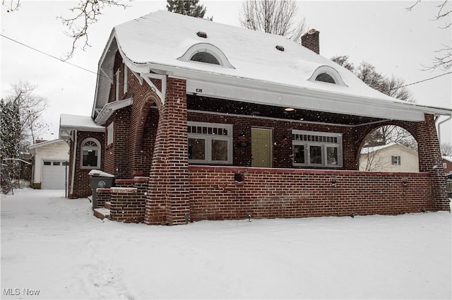 view of snowy exterior with a garage and an outdoor structure