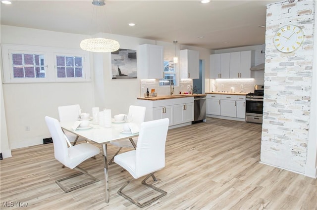 dining space featuring light hardwood / wood-style flooring, a notable chandelier, and sink