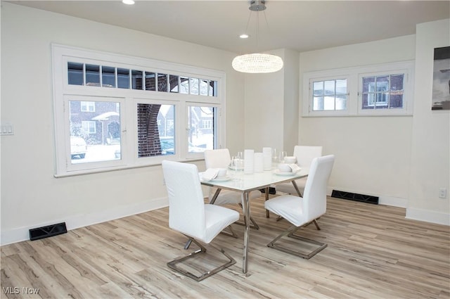 dining area with a wealth of natural light, light hardwood / wood-style flooring, and a chandelier