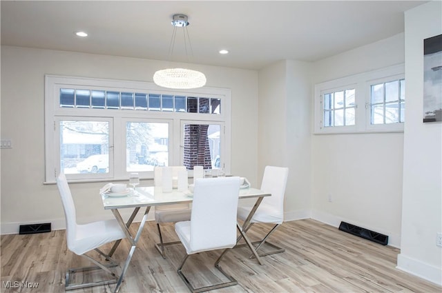 dining room with light hardwood / wood-style floors and an inviting chandelier