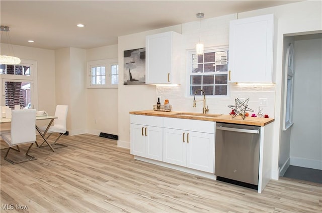 kitchen featuring dishwasher, white cabinets, sink, hanging light fixtures, and butcher block countertops