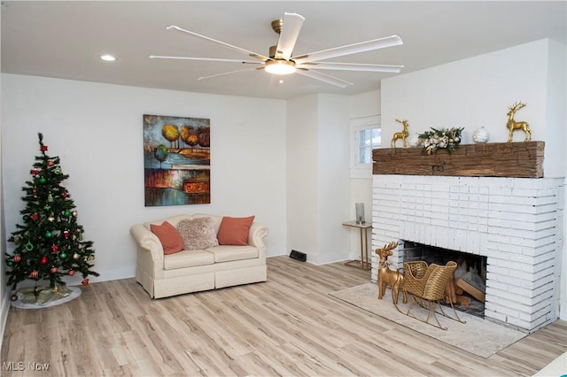 living room with ceiling fan, light wood-type flooring, and a brick fireplace