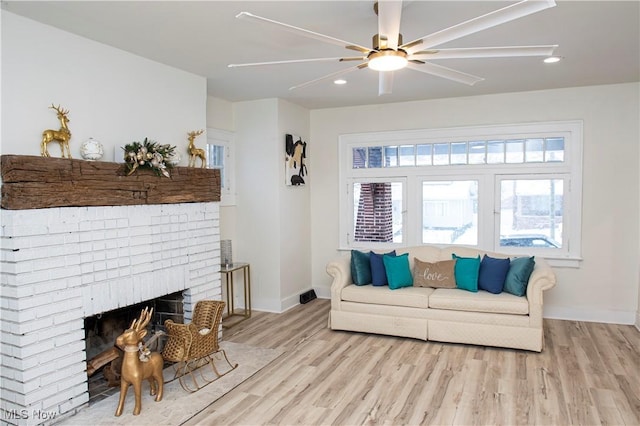 living room featuring ceiling fan, a fireplace, and light hardwood / wood-style floors