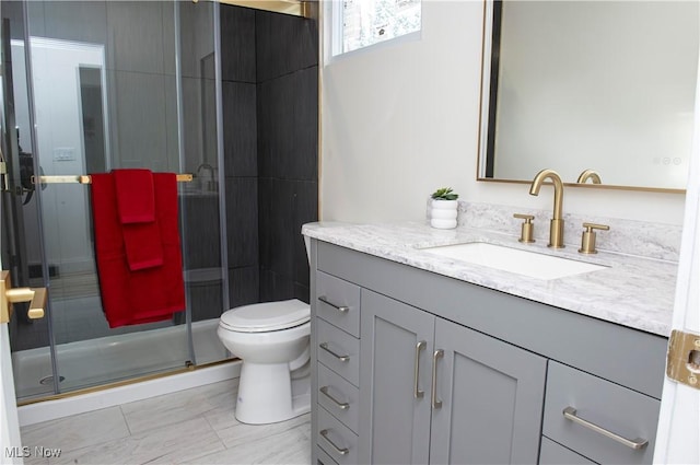 bathroom featuring vanity, toilet, and a shower with shower door