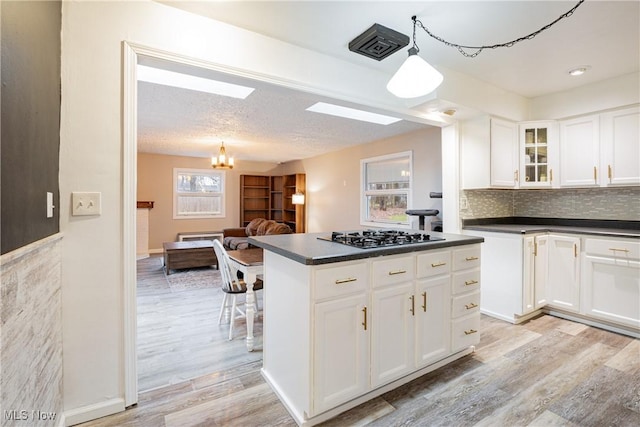 kitchen with a notable chandelier, white cabinets, light hardwood / wood-style flooring, decorative light fixtures, and gas cooktop