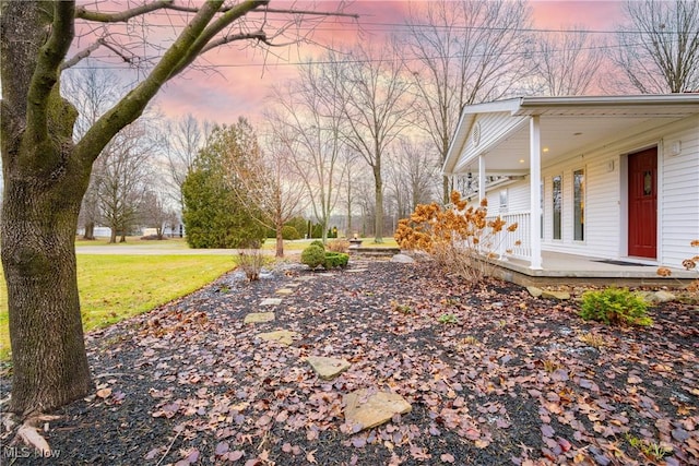 yard at dusk featuring a porch