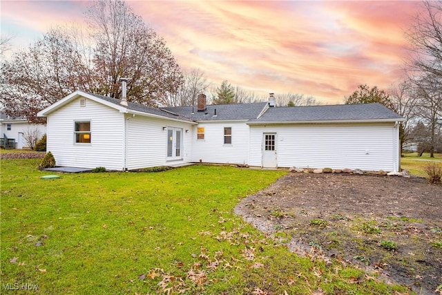 back house at dusk featuring a lawn and french doors