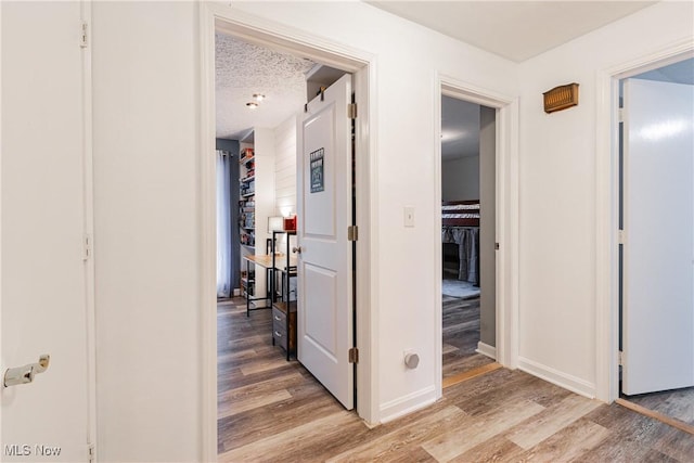 hallway featuring light hardwood / wood-style flooring and a textured ceiling