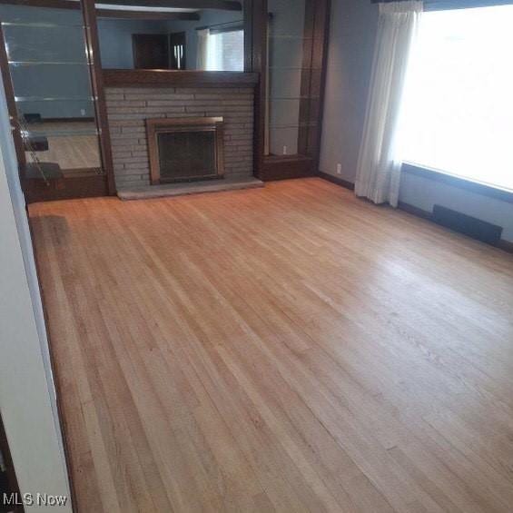 unfurnished living room with light hardwood / wood-style floors and a stone fireplace