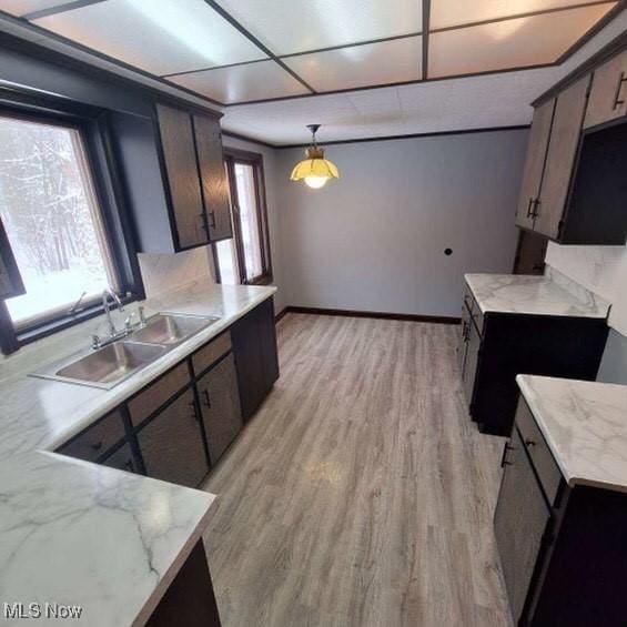 kitchen featuring light wood-type flooring, pendant lighting, dark brown cabinetry, and sink