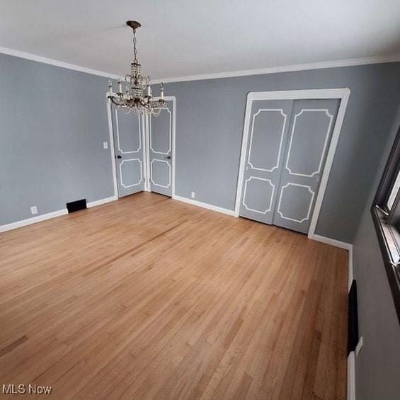 unfurnished dining area with hardwood / wood-style floors, ornamental molding, and an inviting chandelier