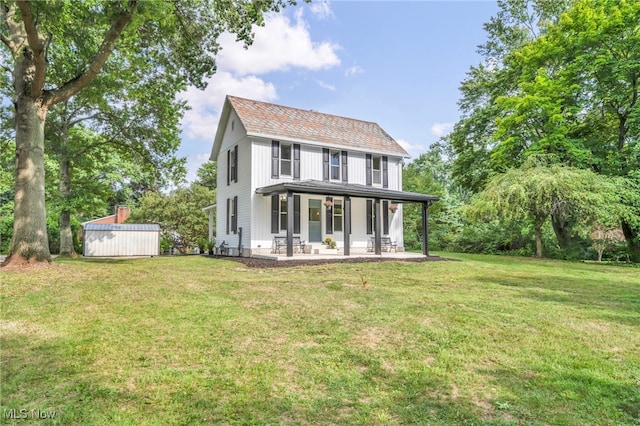 back of house featuring covered porch, a yard, and a shed