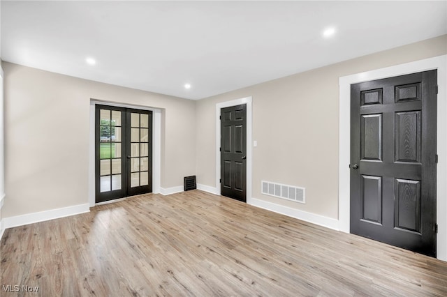 empty room featuring french doors and light hardwood / wood-style flooring