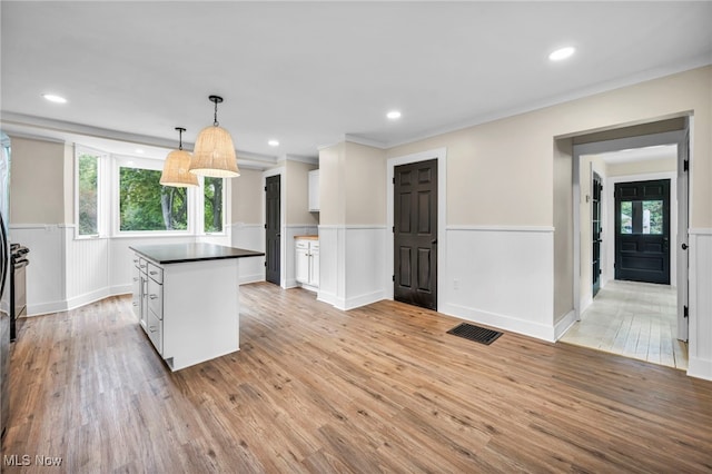 kitchen with white cabinets, plenty of natural light, light wood-type flooring, and hanging light fixtures