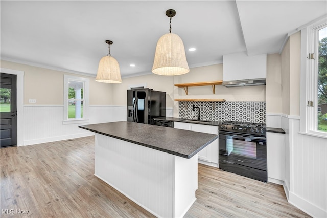 kitchen with ventilation hood, black appliances, decorative light fixtures, light hardwood / wood-style flooring, and white cabinets