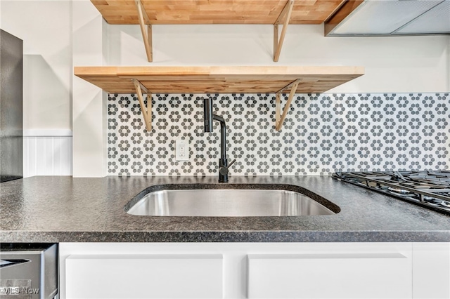 kitchen featuring white cabinets, extractor fan, sink, decorative backsplash, and stainless steel gas cooktop