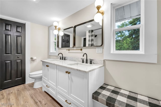 bathroom with a healthy amount of sunlight, vanity, toilet, and hardwood / wood-style floors