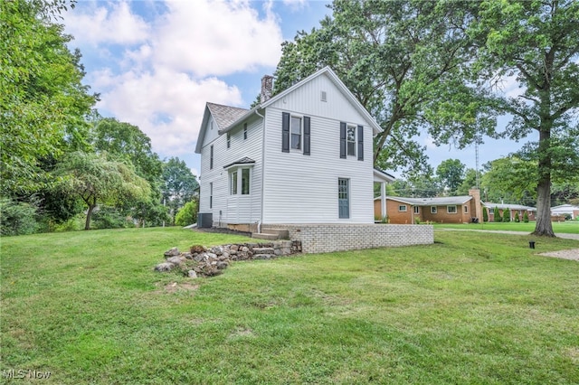 back of house with central AC unit and a lawn