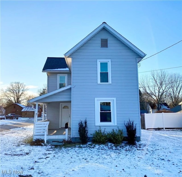 snow covered rear of property with covered porch