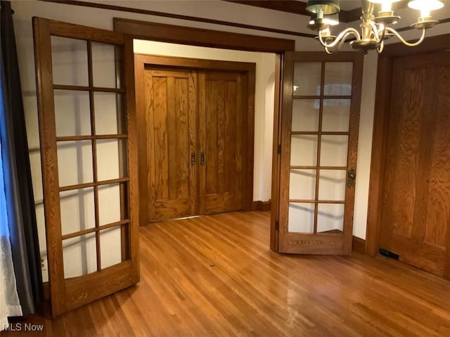 doorway to outside with french doors, light hardwood / wood-style flooring, and a notable chandelier