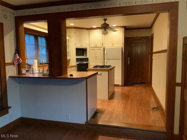 kitchen featuring black appliances, kitchen peninsula, ceiling fan, light wood-type flooring, and white cabinetry