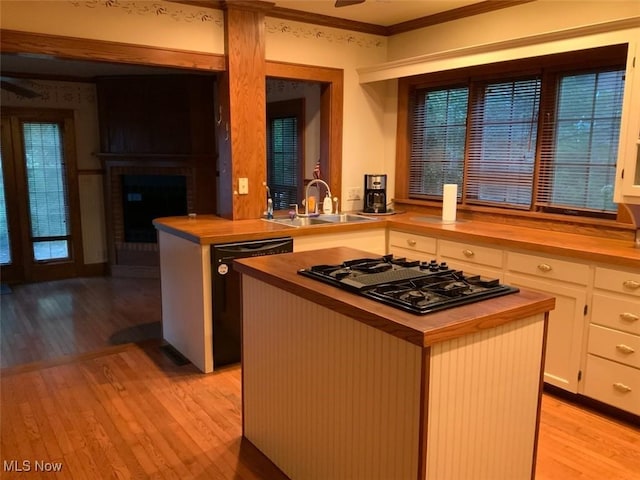 kitchen with a center island, white cabinets, black appliances, sink, and butcher block countertops