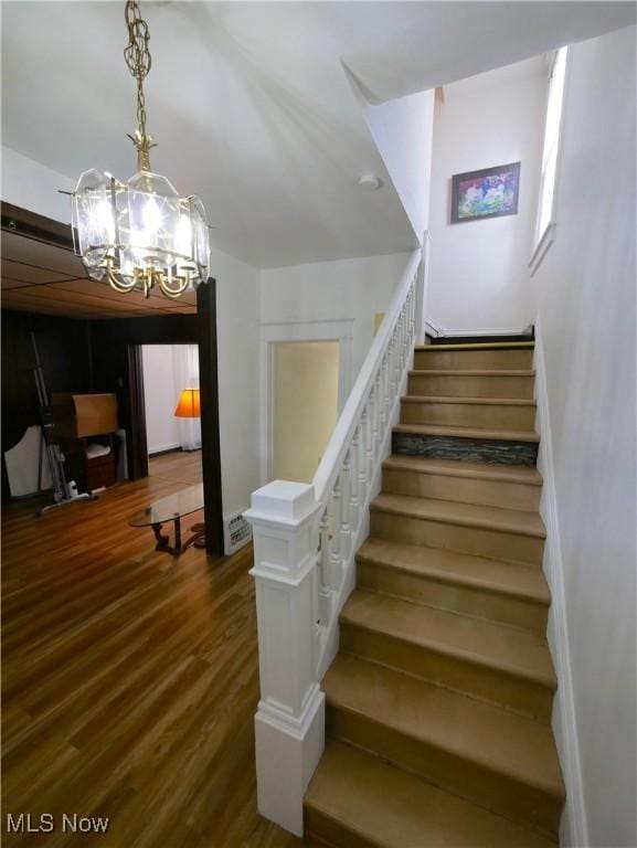 stairway with a chandelier and wood-type flooring