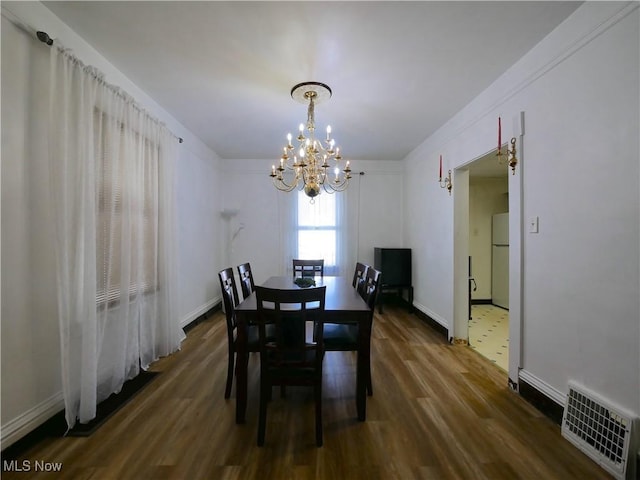 dining area featuring an inviting chandelier and dark wood-type flooring