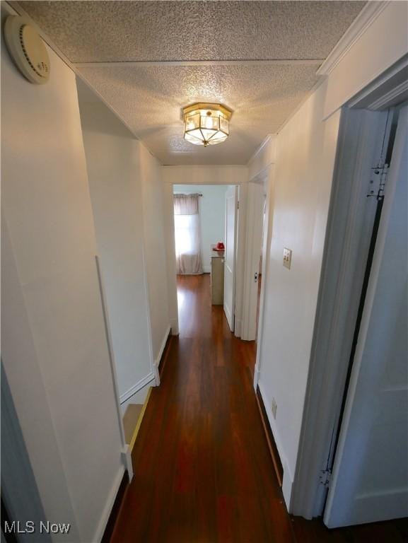 hall featuring dark hardwood / wood-style floors, ornamental molding, and a textured ceiling