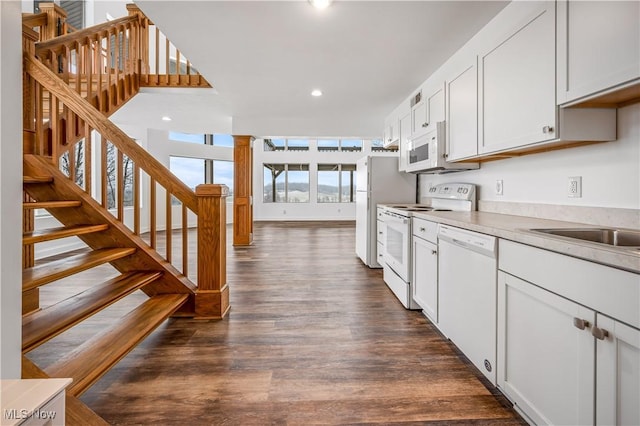 kitchen with sink, white cabinets, dark wood-type flooring, and white appliances