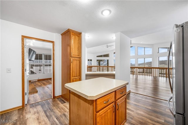 kitchen with ceiling fan, dark wood-type flooring, stainless steel fridge, lofted ceiling, and a kitchen island