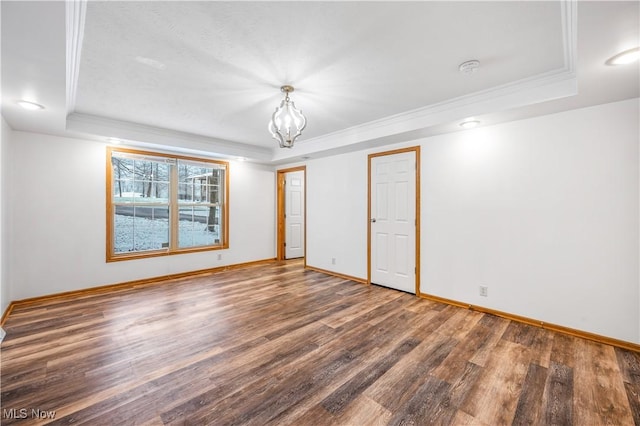 unfurnished room featuring ornamental molding, dark hardwood / wood-style floors, a raised ceiling, and a notable chandelier