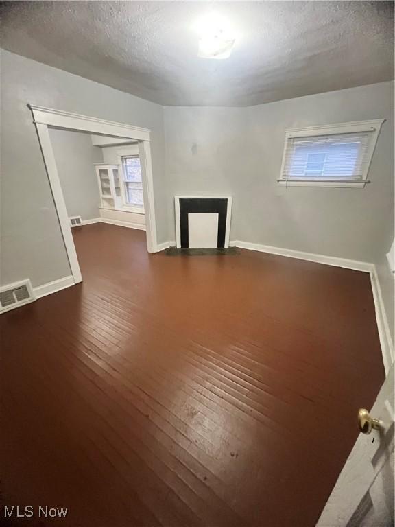 spare room featuring a textured ceiling and dark wood-type flooring