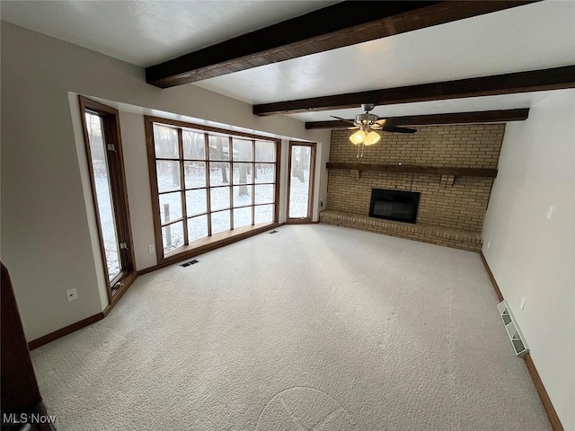 unfurnished living room featuring beamed ceiling, a brick fireplace, carpet floors, and ceiling fan