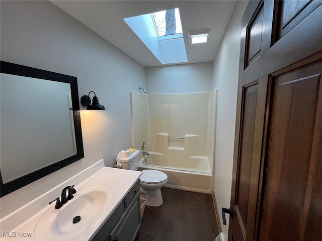 full bathroom with vaulted ceiling with skylight, vanity, wood-type flooring, bathtub / shower combination, and toilet