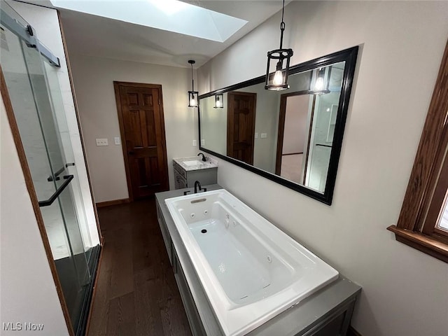 bathroom with wood-type flooring, a bath, a skylight, and vanity