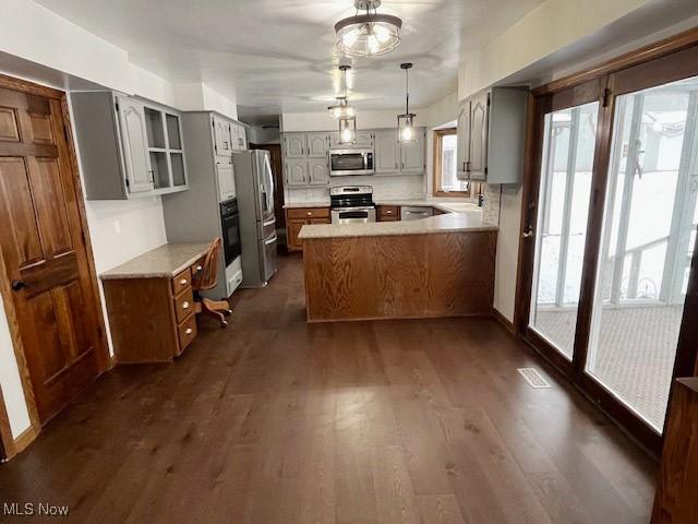 kitchen with dark wood-type flooring, sink, appliances with stainless steel finishes, gray cabinets, and kitchen peninsula