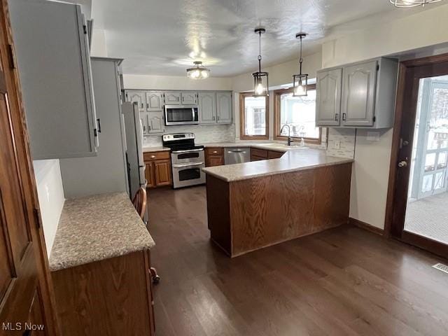 kitchen featuring dark wood-type flooring, sink, tasteful backsplash, decorative light fixtures, and stainless steel appliances