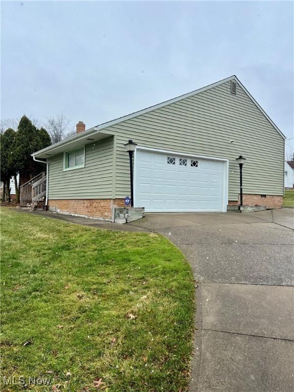 view of side of property featuring a lawn and a garage