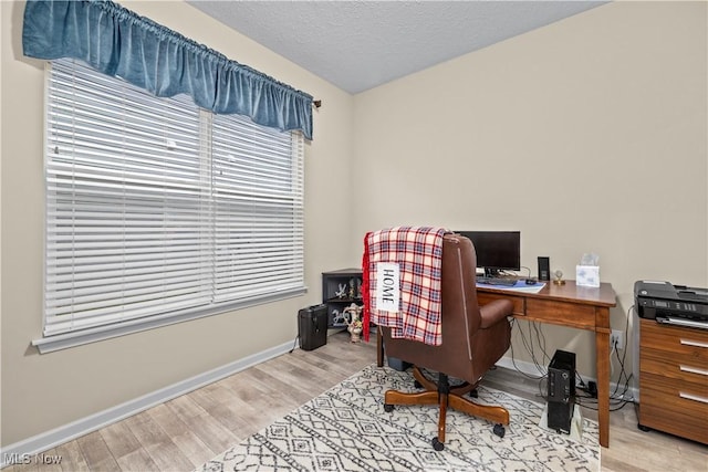 home office with a textured ceiling and light hardwood / wood-style flooring