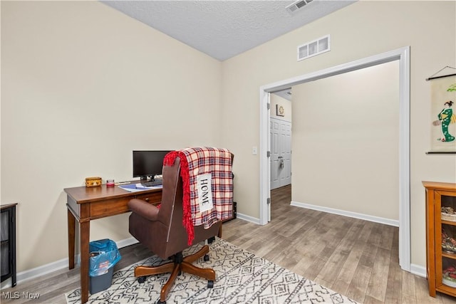 office featuring light wood-type flooring and a textured ceiling